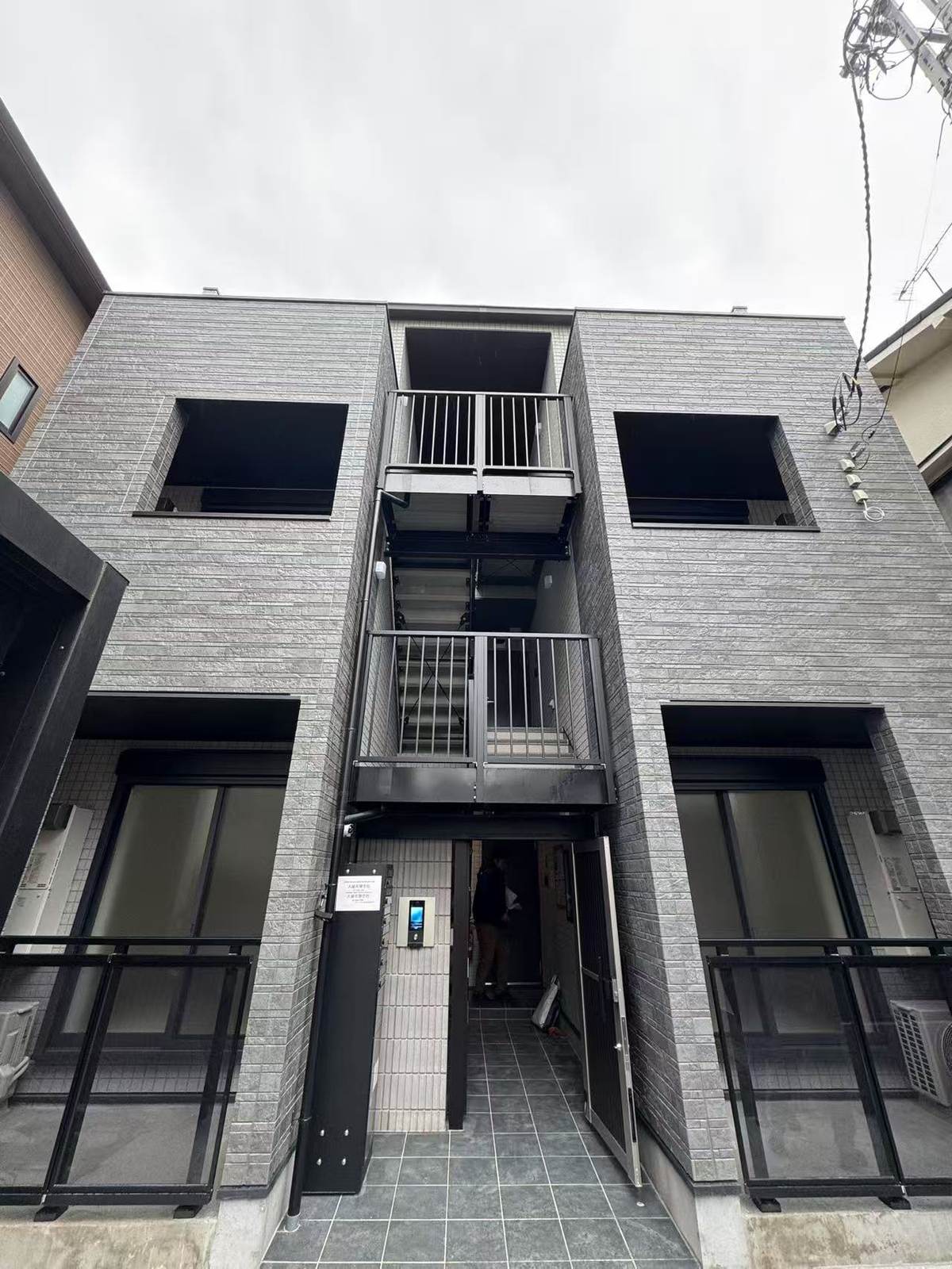 TS・蒲田の外観。グレーのタイル張りに外部階段を備えた建物